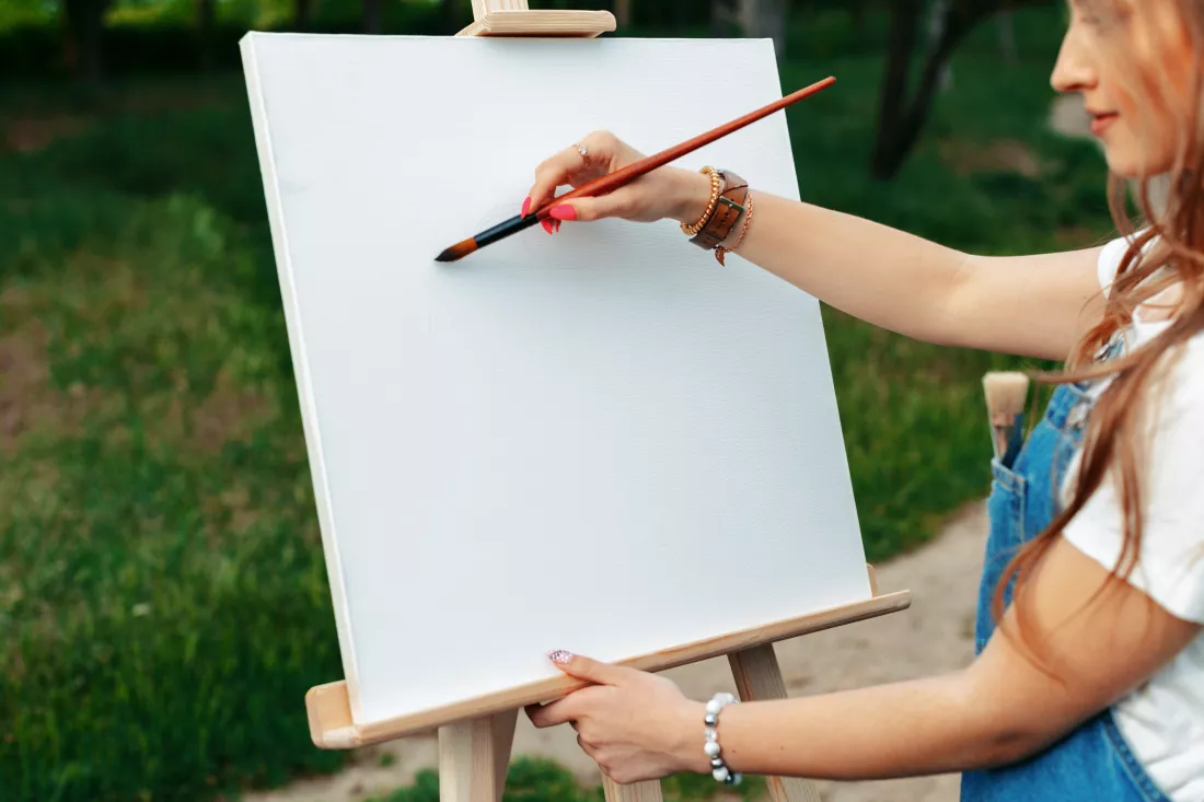 young-caucasian-woman-painting-canvas-outside