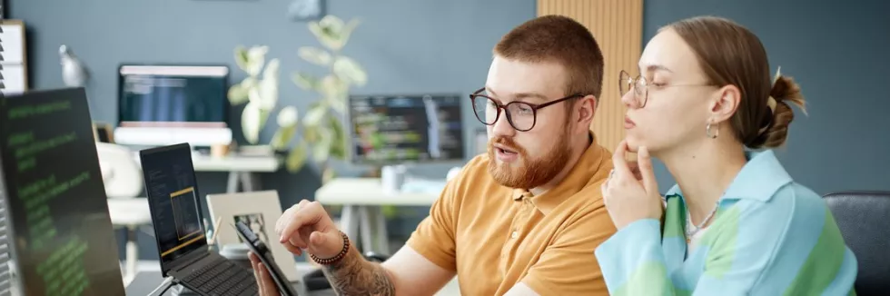 Information-Technology-Masters-test-young-adult-man-explaining-project-to-young-adult-woman