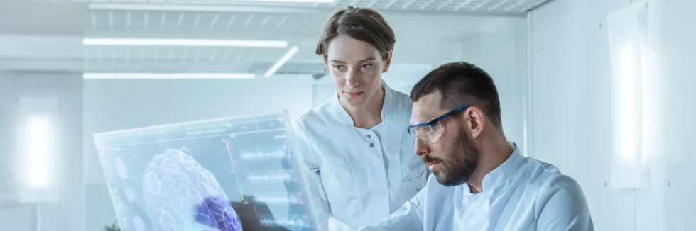 Cognitive-and-Clinical-Neuroscience-Masters-test-two-scientists-in-lab-coats-look-at-a-computer-screen-with-a