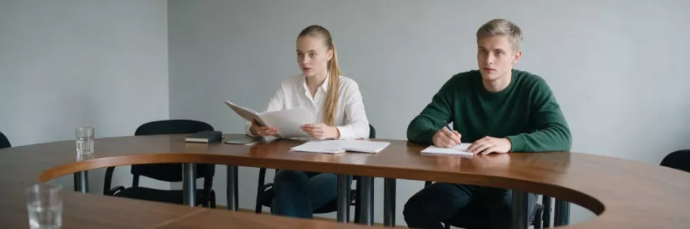 students-holding-a-mock-board-meeting-at-a-long-table