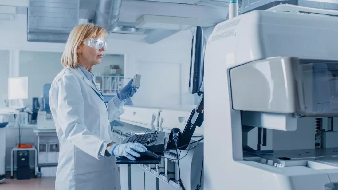woman-lab-wearing-white-coat-goggles-stands-front-large-computer-monitor