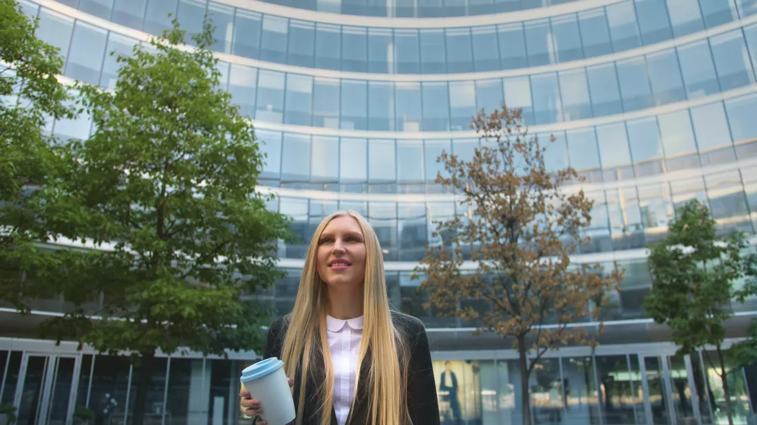 businesswoman-with-long-hair-standing-against-office