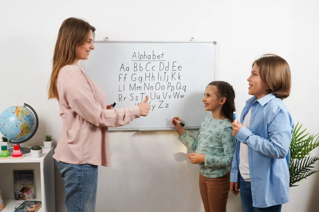 two-schoolchildren-interact-with-their-teacher-english-alphabet-lesson-classroom